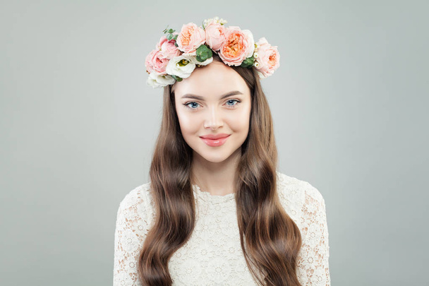 Lente Model vrouw met glanzende krullend haar, natuurlijke make-up en aanbesteding bloemen - Foto, afbeelding