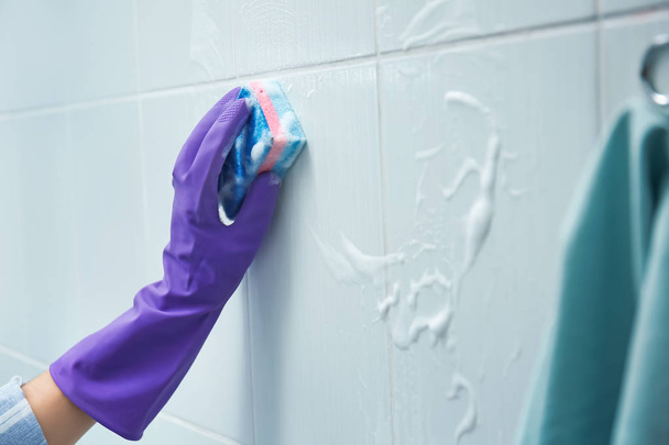 Woman cleaning tiles in bathroom - Foto, afbeelding