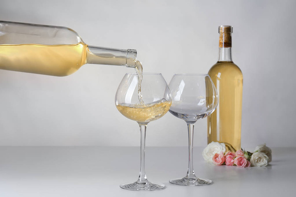 Gieten van wijn in glazen op lichte achtergrond - Foto, afbeelding