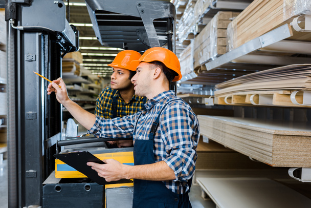 multicultural workers in uniform and plaid shirts working in warehouse - Photo, Image