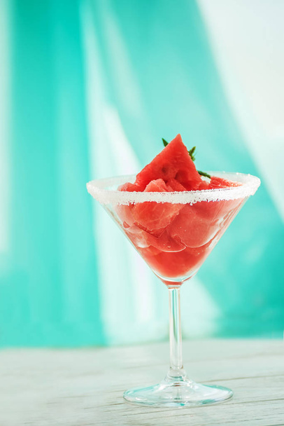 Szelet görögdinnye egy fényes asztal és egy üveg talpas pohár, nyári hangulat. - Fotó, kép