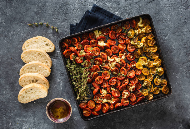 Baked cherry tomatoes into a baking tray on dark background top view - 写真・画像