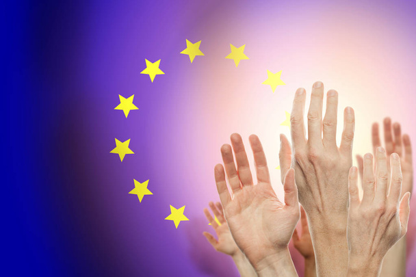 Люди поднимают руки и флаг Союза Европы на заднем плане
. - Фото, изображение