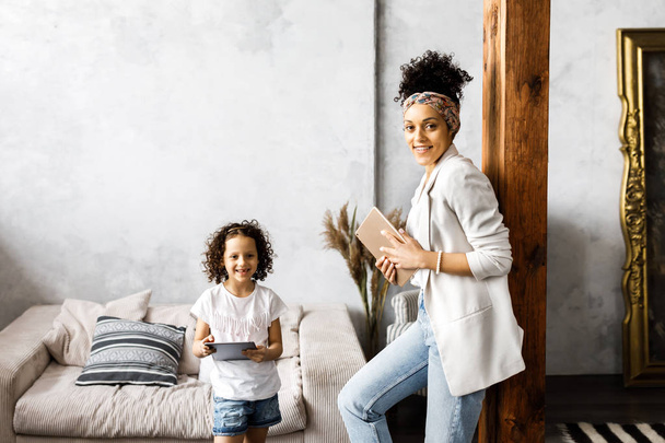 Una simpatica madre e figlia parlare e guardare il tablet mentre in piedi in soggiorno
 - Foto, immagini