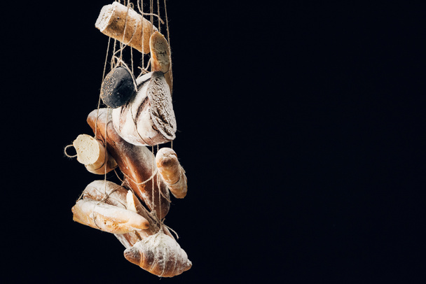 pão fresco assado, baguetes e croissant com farinha pendurada em cordas isoladas em preto com espaço de cópia
 - Foto, Imagem