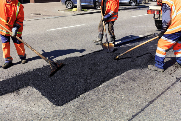 Рабочая бригада очищает часть асфальта лопатами в дорожном строительстве
 - Фото, изображение