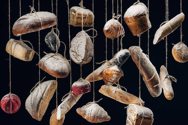 white and brown bread and pastry hanging on ropes isolated on black - Photo, Image