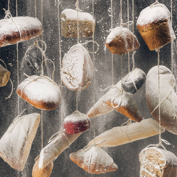 flour falling at homemade bread and pastry hanging on ropes - Φωτογραφία, εικόνα