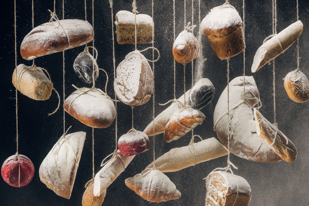 flour falling at fresh homemade bread and pastry hanging on ropes - Фото, зображення