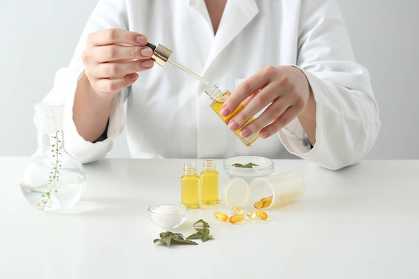 Doctor with natural essential oil at table - Φωτογραφία, εικόνα