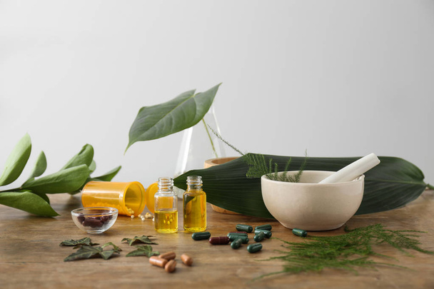 Pillen auf Pflanzenbasis und ätherisches Öl auf Holztisch - Foto, Bild