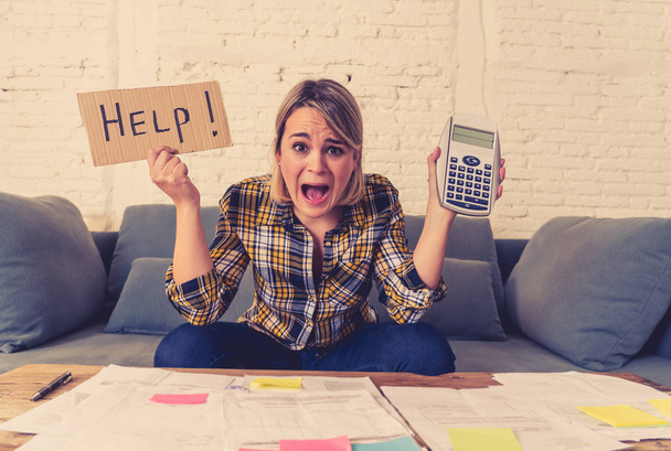 Worried young woman feeling stressed while accounting business and home finances. Desperate showing Help sign and calculator. In bad economic situation, paying debts, bills and financial problems. - Fotó, kép