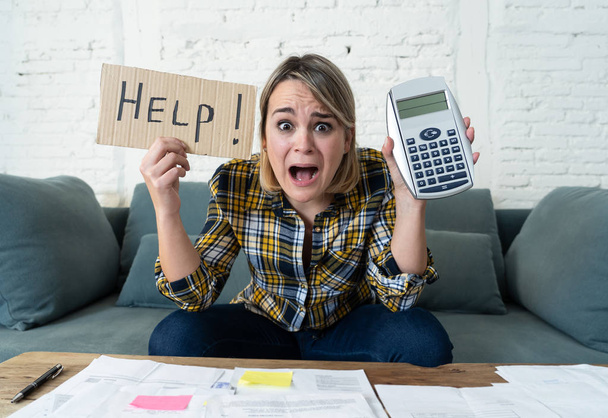Worried young woman feeling stressed while accounting business and home finances. Desperate showing Help sign and calculator. In bad economic situation, paying debts, bills and financial problems. - Fotoğraf, Görsel