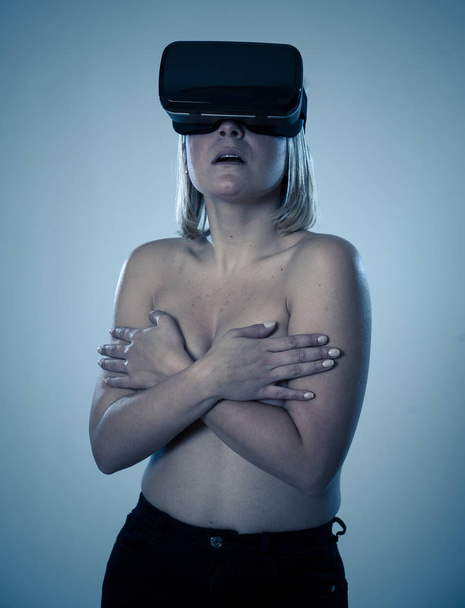 Sensual attractive woman using augmented or virtual reality goggles feeling excited exploring virtual sexuality while getting topless covering her breast. In cyber sex VR simulator and new technology. - Foto, immagini