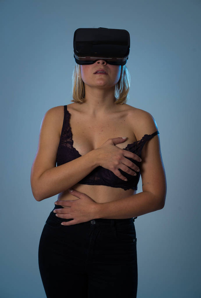 Чуттєва жінка, використовуючи доповнені окуляри віртуальної реальності, захоплюється симуляцією, вивчає віртуальну сексуальність в сексуальному чорному бюстгальтері і збуджується. " Секс і нова технологія "
. - Фото, зображення