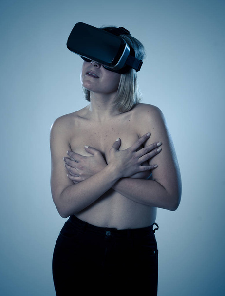 Sensual attractive woman using augmented or virtual reality goggles feeling excited exploring virtual sexuality while getting topless covering her breast. In cyber sex VR simulator and new technology. - Fotografie, Obrázek