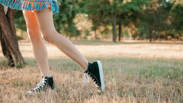 Pernas elegantes de uma mulher andando no campo de grama
 - Foto, Imagem