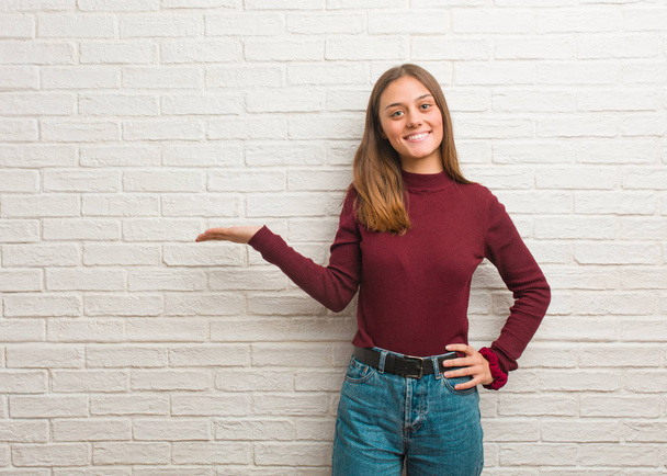 Jeune femme cool sur un mur de briques tenant quelque chose avec la main
 - Photo, image