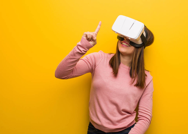 Young cute woman wearing a virtual reality googles showing number one - Foto, Bild