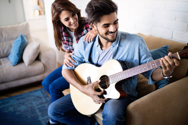 Young handsome man playing guitar for his beautiful girlfriend - Fotoğraf, Görsel