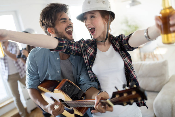 Group of happy friends playing guitar and partying at home - Foto, Imagen
