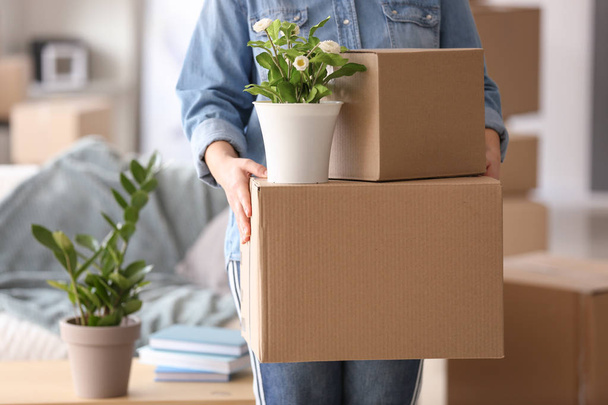 Γυναίκα με κινούμενα κουτιά και το φυτό στο δωμάτιο - Φωτογραφία, εικόνα