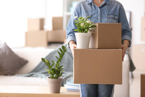 Woman with moving boxes and plant in room - Foto, afbeelding
