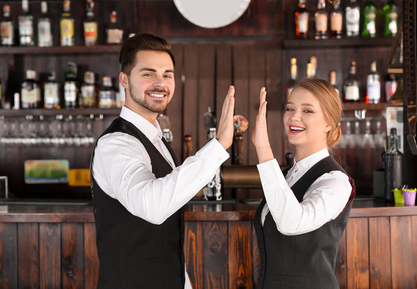 Młodzi kelnerzy dając sobie nawzajem High-Five w restauracji - Zdjęcie, obraz