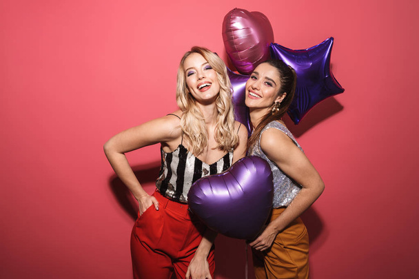 Image of two joyous girls 20s in stylish outfit laughing and hol - Foto, Bild