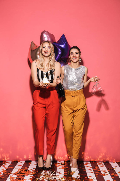 Photo of two joyful women 20s in stylish outfit holding festive  - Foto, afbeelding