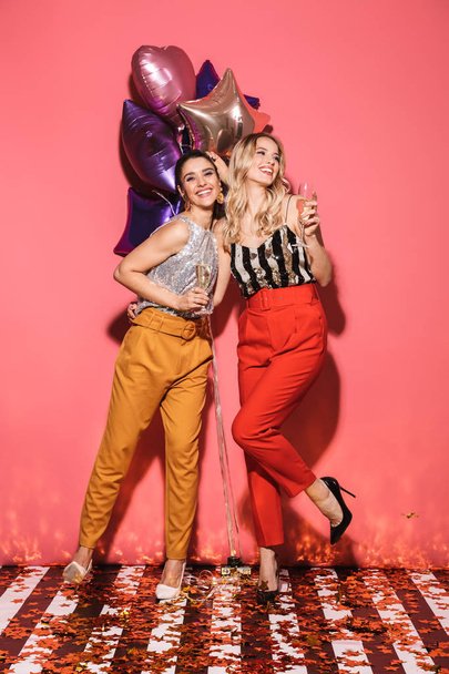 Photo of two happy women 20s in stylish outfit holding festive b - Zdjęcie, obraz