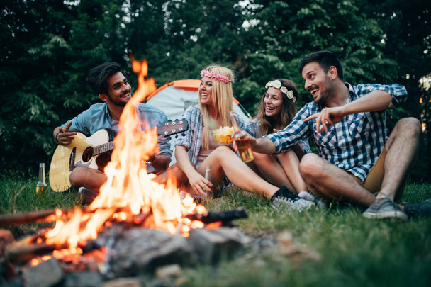 Happy friends playing music and enjoying bonfire in nature - Фото, зображення