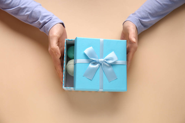 Manos femeninas con caja de regalo sobre fondo de color - Foto, Imagen