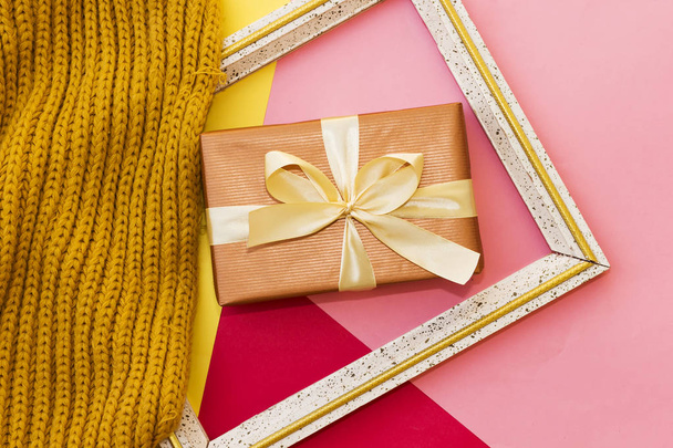 rectangle gift box on three color paper with wooden frame photo and winter scarf on  red, yellow and pink background - Fotoğraf, Görsel