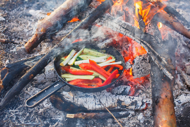 Cooking dishes from red bell peppers and cucumbers in a pan on a fire - Foto, Bild