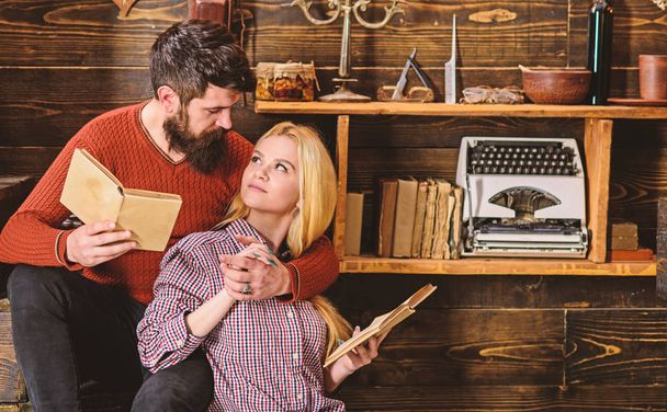 Friends reading book and studying at loft vintage apartments. Woman and attractive man wearing casual clothes learning languages at cozy home. Lovely couple together - Foto, Bild