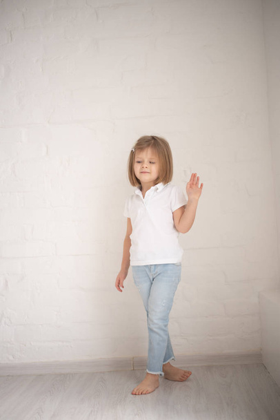 Повна довжина красивої маленької дівчинки в сукні стоїть і позує на білому тлі
 - Фото, зображення
