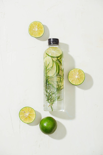 Health care, fitness, healthy nutrition diet concept. Fresh cool lemon rosemary infused water, cocktail, detox drink, lemonade in a glass jar. Light top view flat lay background - Foto, Bild