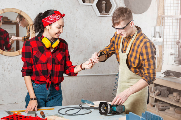 Man and woman carpenters working together in a wood workshop. Co - 写真・画像
