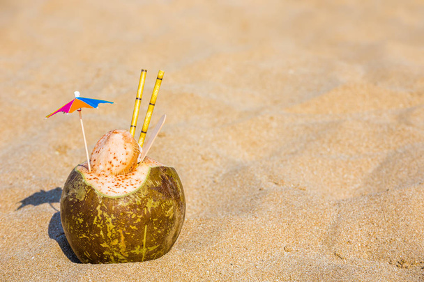 Coconut with an umbrella and a tube on the background of the sea  - Фото, зображення