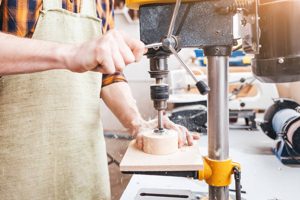 El primer plano del carpintero por las manos que trabajan con la madera sobre el torno la perforación
 - Foto, imagen