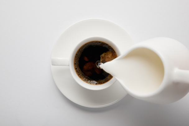 Top view of cup of coffee and jug of milk on white - Fotografie, Obrázek