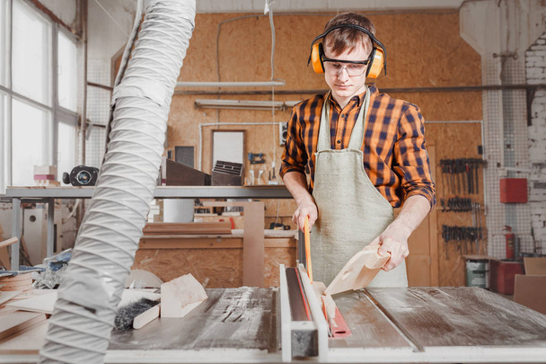 Artesano masculino que trabaja con la máquina de sierra automatizada en fábrica o
  - Foto, imagen