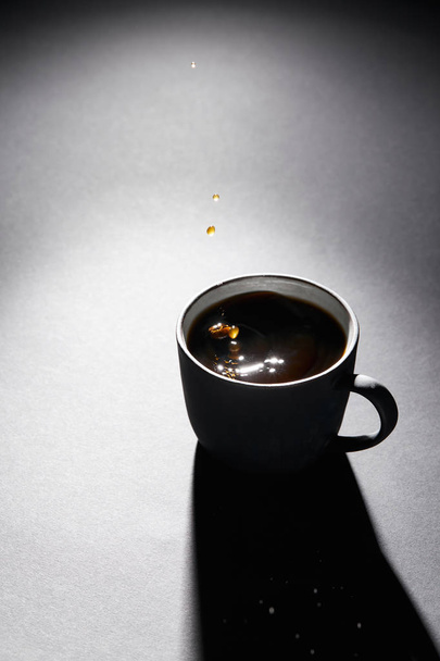 Cup full of coffee with drops on dark textured surface - Φωτογραφία, εικόνα