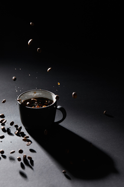 Coffee cup and coffee grains on dark textured surface - Foto, Imagem