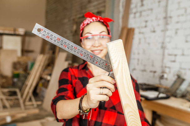Mujer profesional trabaja con madera y la mide con una regla
  - Foto, Imagen