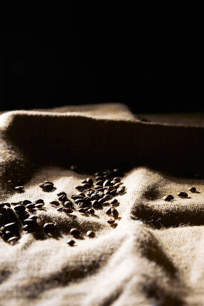 Selective focus of roasted coffee grains on sackcloth texture - Photo, Image