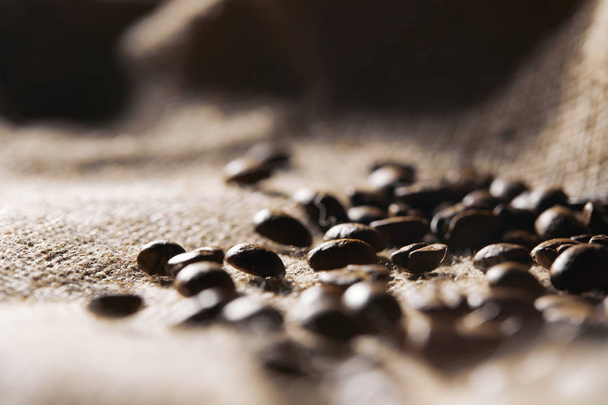 Selective focus of roasted coffee grains on sackcloth texture - Foto, imagen