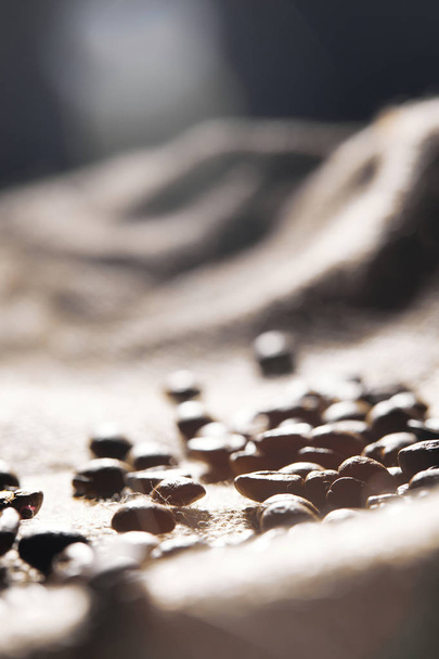 Selectieve focus van geroosterde koffie korrels op zak textuur - Foto, afbeelding