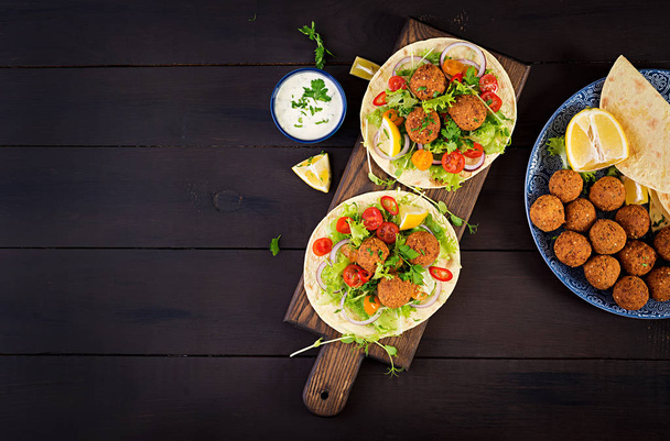 Тортилья с фалафелем и свежим салатом. Веганские тако. Вегетарианская здоровая еда. Вид сверху
 - Фото, изображение